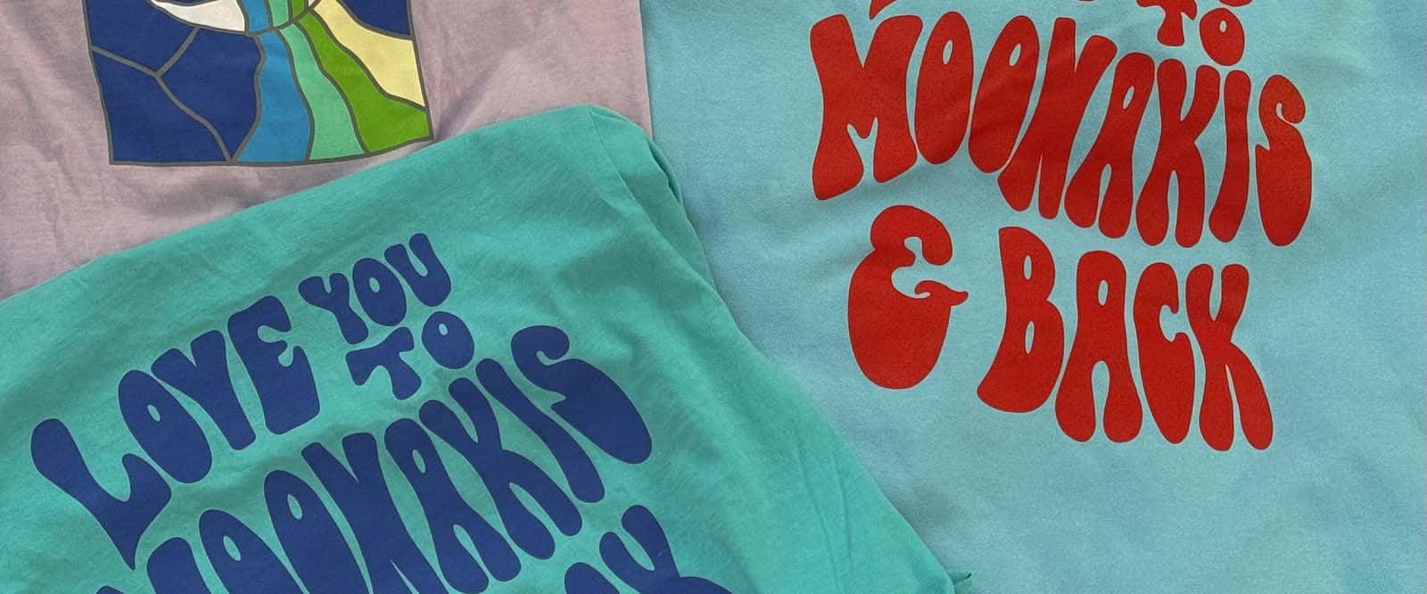 Love you to Moonakis and back shirts in teal and light blue beside the lavender moon-print tee