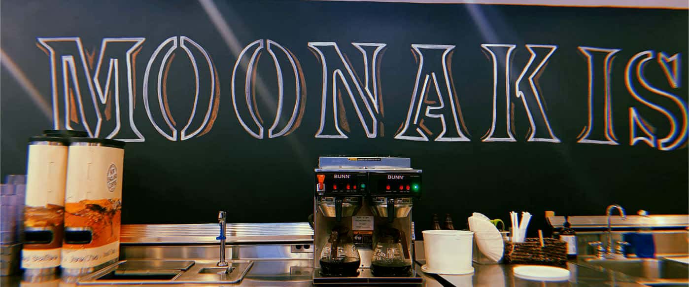 Hand-painted MOONAKIS lettering on the cafe's dark wall above the coffee station
