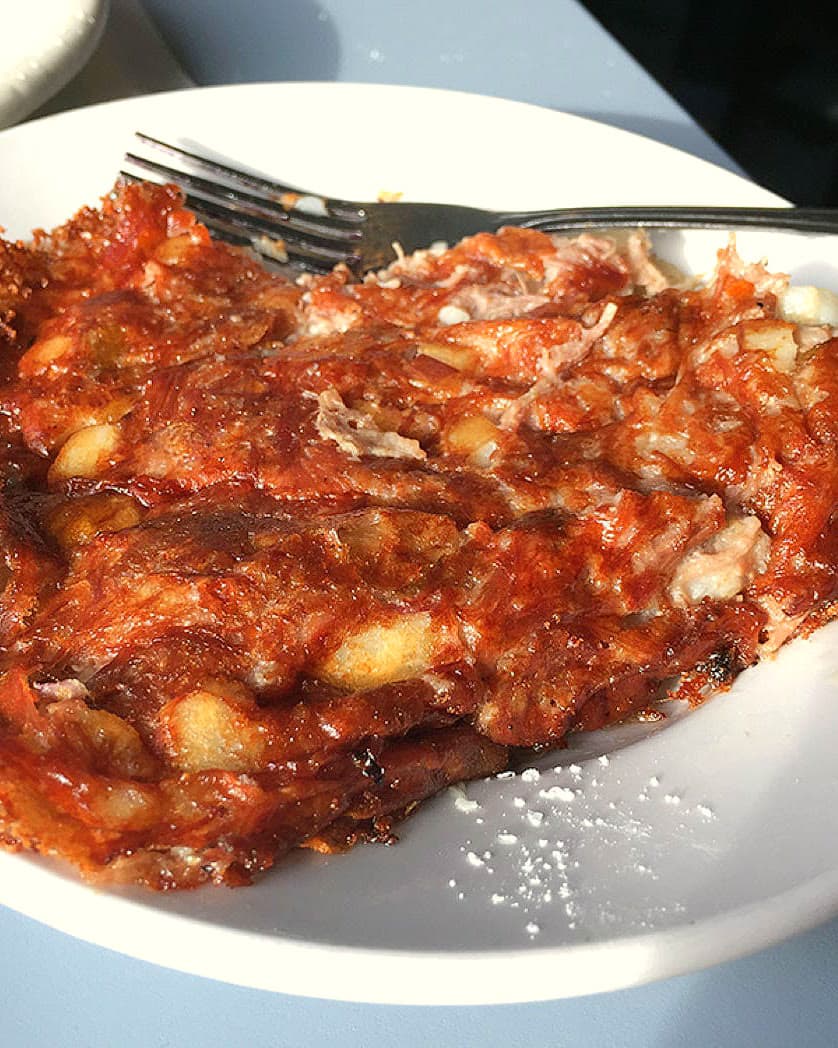 Crisp homemade corned beef hash filling a white plate, a fork resting at the top edge