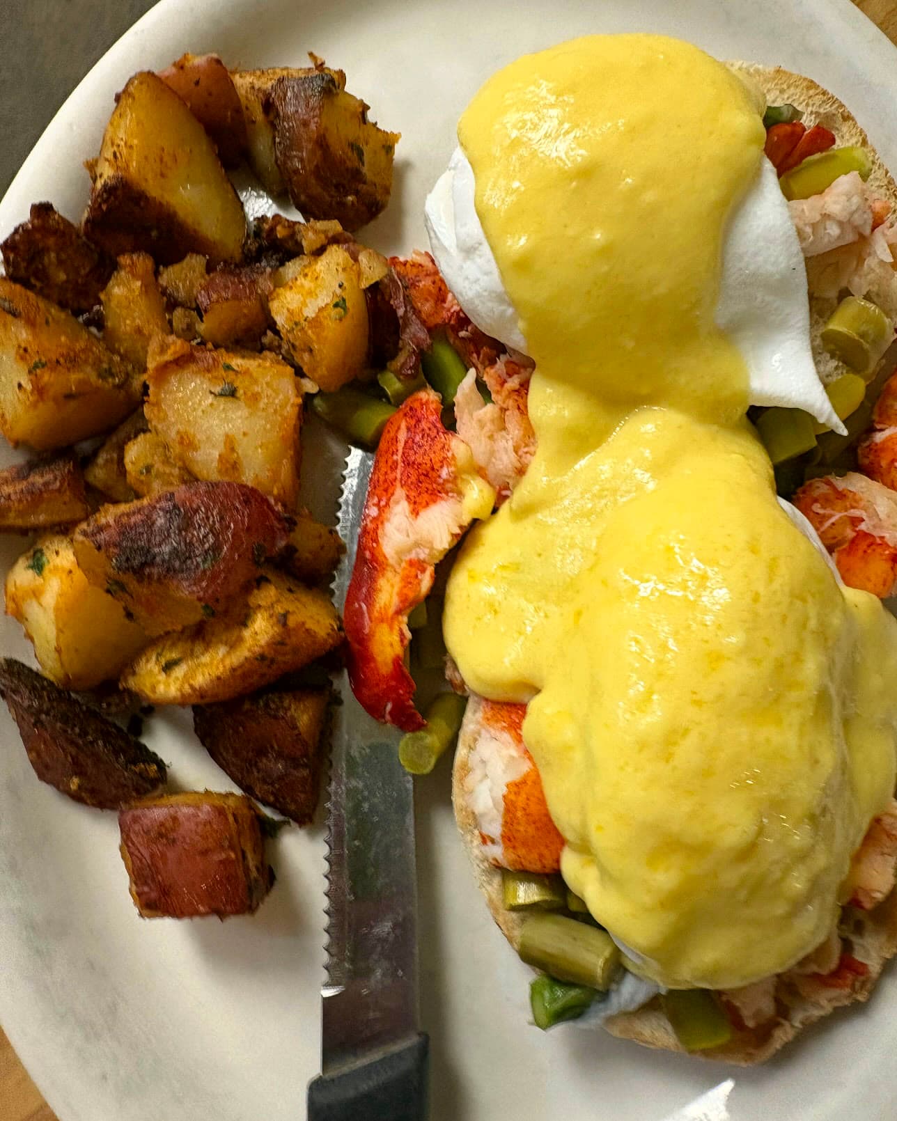 Lobster benedict: poached eggs and hollandaise over lobster meat and asparagus on an english muffin, home fries alongside